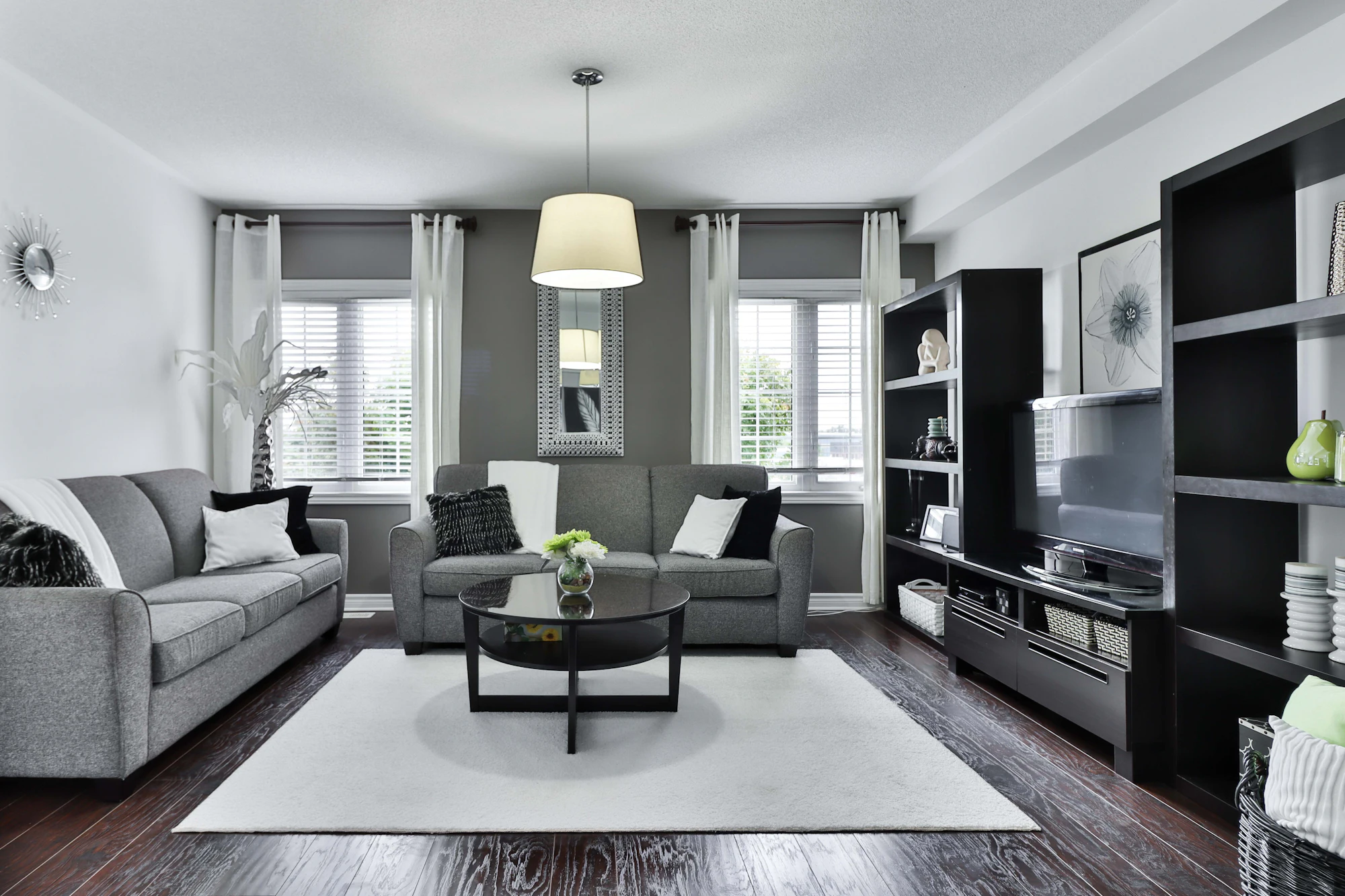 Bright contemporary living room with grey sofa, armchairs and large windows