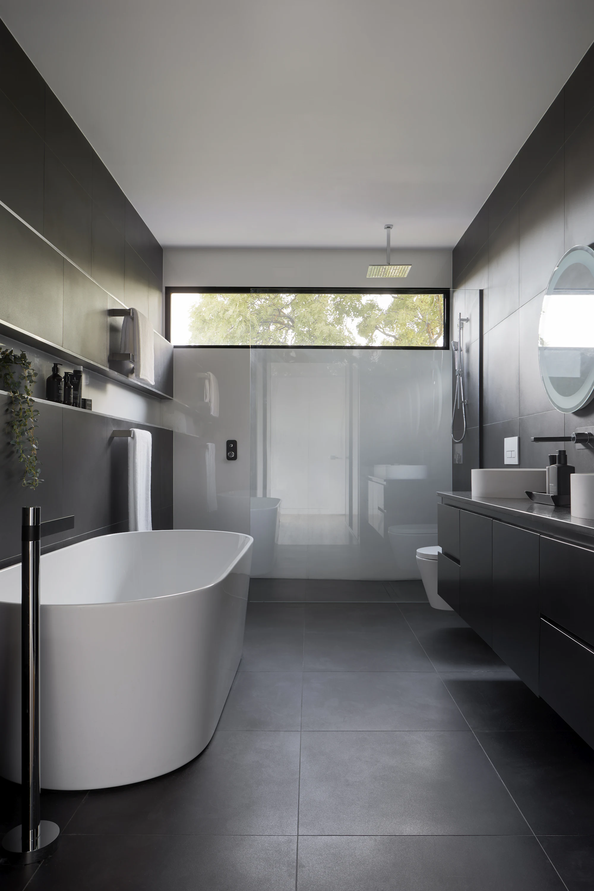 Dark luxury bathroom with stone finishes, freestanding tub and ambient lighting