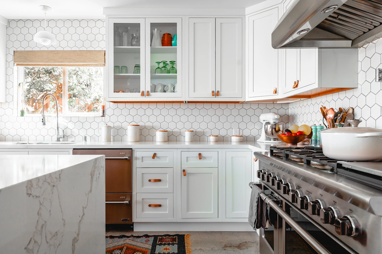 Classic white modular kitchen with marble counters, glass-front cabinets and range hood
